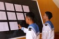 Hai chiến sỹ trẻ lần đầu tiên được đi bầu, theo dõi danh sách cử tri được niêm yết tại UBND xã Song Tử Tây, huyện Trường Sa (Khánh Hòa). Ảnh: TTXVN