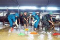 Lực lượng quân đội, dân quân tự vệ đẩy bùn đất, tổng dọn vệ sinh tại chợ xã Thanh Mỹ, huyện Thanh Chương (Nghệ An). Ảnh: Tá Chuyên - TTXVN