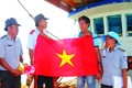 薄辽省渔政力量向船东和船长赠送国旗，鼓励与动员渔民继续出海谋生。图自越通社