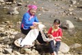 Chị Sùng Thị Lan (phải) buộc sỏi để chuẩn bị nhuộm vải. Ảnh: nongnghiep.vn