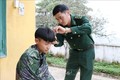 Trung úy Dì A De, Đội trưởng Đội Ma túy Đồn Biên phòng Thu Lũm cắt tóc cho cháu Mạ Đức Mạnh. Ảnh: Hoàng Thùy Oanh – TTXVN