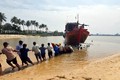 Người dân địa phương hỗ trợ lai dắt và trục vớt thuyền bị chìm của ngư dân đưa vào bờ. Ảnh: TTXVN phát