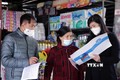 Nhân viên Bảo hiểm xã hội tỉnh Lai Châu tuyên truyền, vận động người dân tại chợ Trung tâm Thương mại thành phố Lai Châu tham gia bảo hiểm xã hội, bảo hiểm y tế tự nguyện. Ảnh: Quý Trung – TTXVN