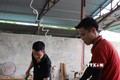 Anh Phùng Bình Minh (mặc áo đen) hướng dẫn công nhân kỹ thuật đóng tấm Pallet. Ảnh: Tiến Khánh - TTXVN