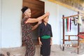 Bà Vi Thị Dung hướng dẫn cách mặc trang phục truyền thống cho thế hệ trẻ. Ảnh: Xuân Tiến - TTXVN