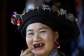 Phụ nữ Lào dùng tay quệt nhựa cây “mạy tửu” bôi lên răng để nhuộm. Ảnh: Việt Nguyên