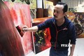 Họa sĩ Ngô Thanh Hùng sáng tác tranh tại nhà. Ảnh: Văn Dũng - TTXVN
