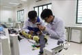 Phạm Đức Linh và Nguyễn Văn An cùng nhau nghiên cứu sản phẩm Cánh tay robot cho người khuyết tật liệt cơ tay toàn phần. Ảnh: Thanh Thương- TTXVN
