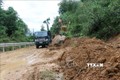 Khẩn trương dọn bùn, đất để người dân lưu thông trên đường tỉnh lộ 622B. Ảnh: Sỹ Thắng - TTXVN

