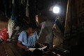 Em Đinh Thị Khơ, làng Mang Ve, học bài dưới ánh đèn năng lượng nguồn sáng yếu ớt. Ảnh: Phạm Cường-TTXVN T
