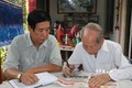 Ông Nguyễn Văn Thọ (phải) và con trai Nguyễn Thanh Hà đọc thông tin ở mục tìm thân nhân liệt sĩ trên báo. Ảnh: Hữu Chí – TTXVN 