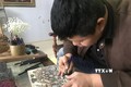 Anh Nguyễn Công Đạt làng Thanh Liễu khắc bản gỗ với tích rùa thần nhận gươm báu ở Hồ Hoàn Kiếm. Ảnh: Tiến Vĩnh - TTXVN