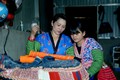 Chị Lầu Thị Tro hướng dẫn con gái cách thêu hoa văn trên trang phục truyền thống. Ảnh: Quang Quyết