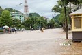 Lực lượng Cảnh sát giao thông, Công an thành phố Sơn La, giúp người dân đi qua đoạn đường bị ngập nước ở khu vực đường Trường Chinh, phường Quyết Thắng. Ảnh: Nguyễn Cường - TTXVN