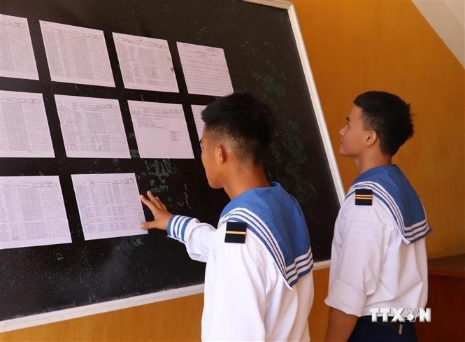 Hai chiến sỹ trẻ lần đầu tiên được đi bầu, theo dõi danh sách cử tri được niêm yết tại UBND xã Song Tử Tây, huyện Trường Sa (Khánh Hòa). Ảnh: TTXVN