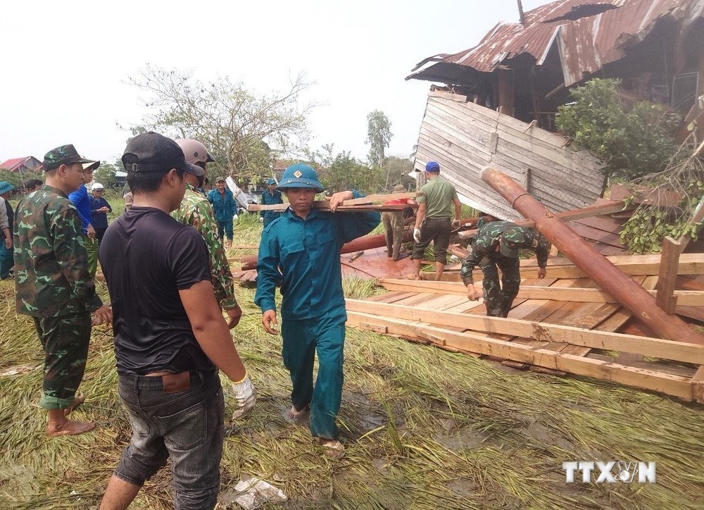 Các lực lượng chức năng hỗ trợ người dân khắc phục thiệt hại do mưa dông, lốc. Ảnh: TTXVN phát
