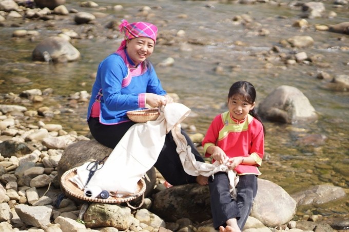 Chị Sùng Thị Lan (phải) buộc sỏi để chuẩn bị nhuộm vải. Ảnh: nongnghiep.vn