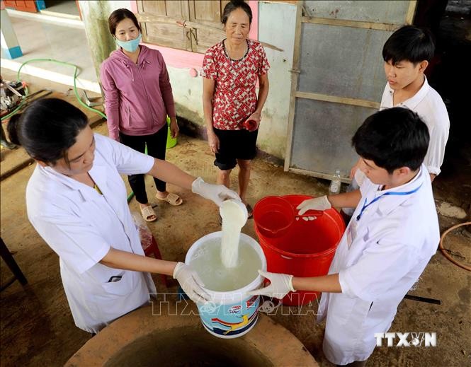 Nhân viên Trung tâm Y tế dự phòng huyện Lệ Thủy tiến hành khử khuẩn nước sinh hoạt bằng dung dịch Cloramin B cho hộ Lê Thị Đào ở thôn Mai Thúy, xã Mai Thủy. Ảnh: Vũ Sinh - TTXVN