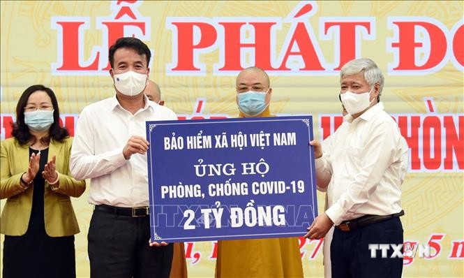 Chủ tịch Ủy ban Trung ương Mặt trận tổ quốc Việt Nam Đỗ Văn Chiến (bên phải) tiếp nhận 2 tỷ đồng của BHXH Việt Nam ủng hộ. Ảnh: TTXVN