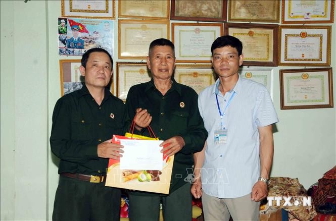 Đại diện Hội Cựu chiến binh huyện Mường La và xã Mường Bú đến tặng quà thương binh 4/4 Quàng Văn Sơn (ở giữa) tại bản Giàn, xã Mường Bú. Ảnh: Quang Quyết-TTXVN