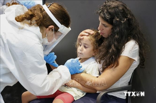 Nhân viên y tế lấy mẫu xét nghiệm COVID-19 cho trẻ em tại Tel Aviv, Israel ngày 19/8/2021. Ảnh: AFP/TTXVN