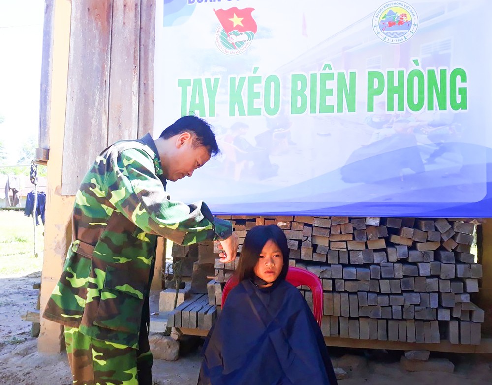 Thượng tá Nguyễn Xuân Linh, Chính trị viên Đồn Biên phòng Cửa khẩu quốc tế La Lay cắt tóc cho trẻ em Lào. Ảnh: baoquangtri.vn