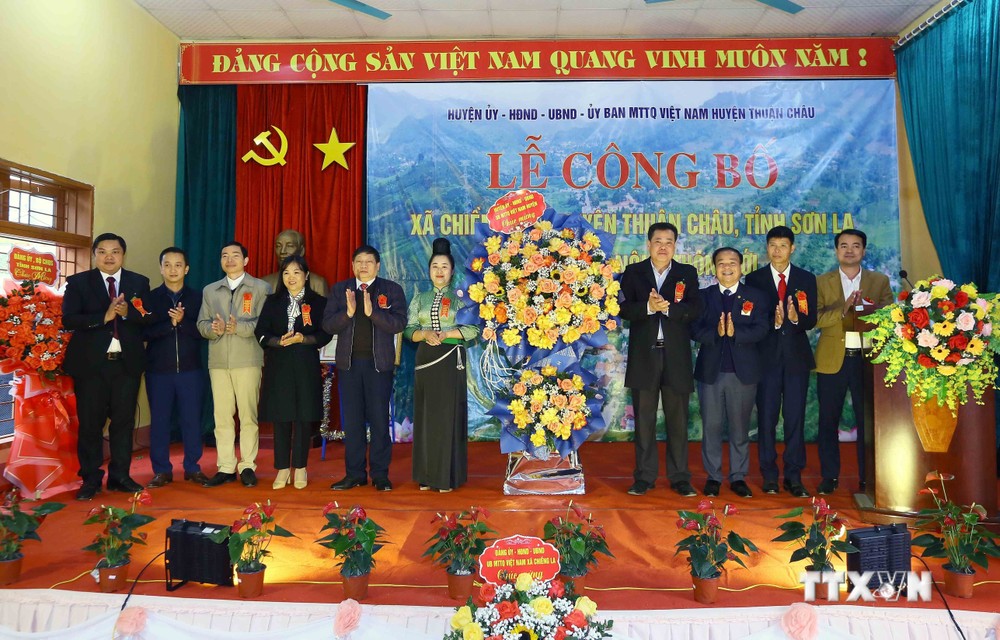 Lãnh đạo huyện Thuận Châu tặng hoa chúc mừng xã Chiềng Pha đạt chuẩn nông thôn mới. Ảnh: Quang Quyết - TTXVN
