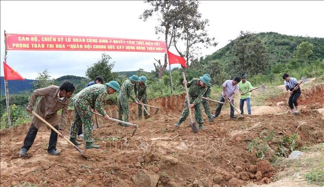 Bộ đội Lữ đoàn 7 và người dân làng Đê Kôn san gạt đất làm đường về làng. Ảnh: Hồng Điệp - TTXVN
