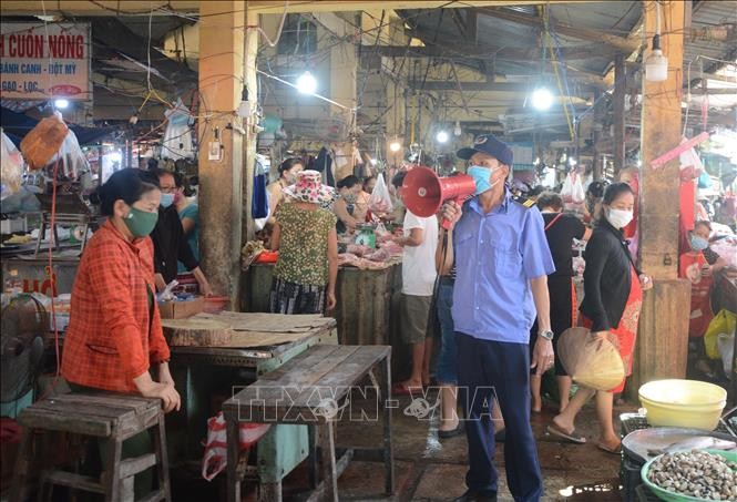 Cán bộ quản lý chợ Mai (phường Thọ Quang, quận Sơn Trà) tuyên truyền, nhắc nhở người dân chấp hành nghiêm chỉnh các biện pháp phòng, chống COVID-19. Ảnh: Văn Dũng - TTXVN