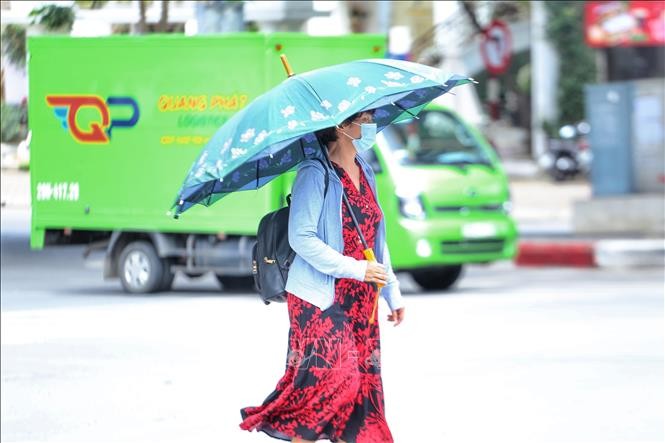 Áo chống nắng và ô là vận dụng không thể thiếu của người dân khi ra đường. Ảnh: TTXVN