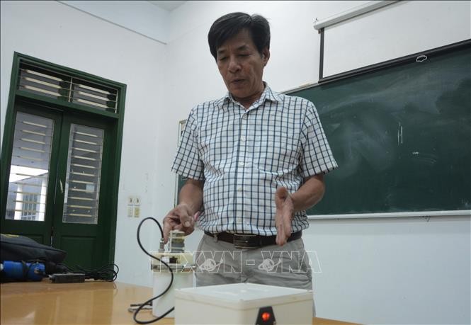 Thầy Nguyễn Văn Thịnh thuyết minh về nguyên lý hoạt động của máy nghiền bi trục đứng. Ảnh: Văn Dũng – TTXVN