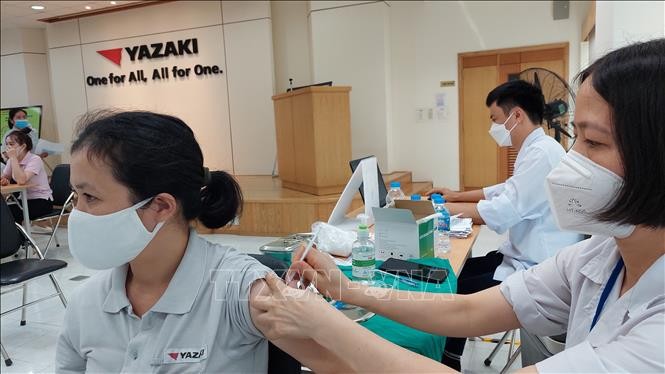 Các công nhân phấn khởi vì được ưu tiên tiêm vaccine mũi 4 để yên tâm sản xuất. Ảnh: Thanh Vân-TTXVN