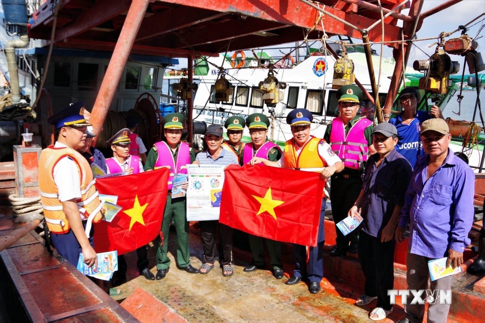 Lực lượng phối hợp tuyên truyền, trao cờ cho ngư dân. Ảnh: TTXVN phát