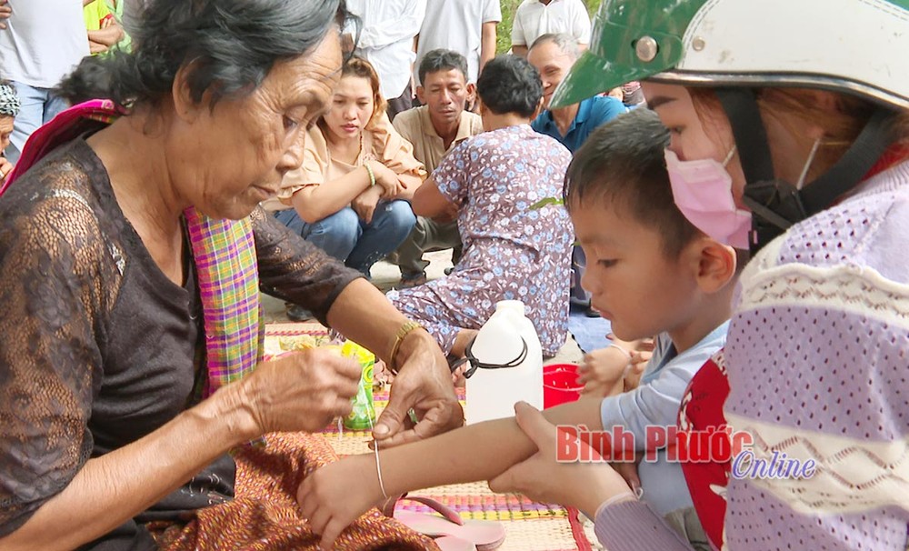 Trẻ em được những người lớn tuổi cột chỉ tay cầu an trong ngày lễ hội. Nguồn:baobinhphuoc.com.vn