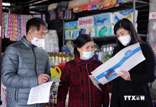 Nhân viên Bảo hiểm xã hội tỉnh Lai Châu tuyên truyền, vận động người dân tại chợ Trung tâm Thương mại thành phố Lai Châu tham gia bảo hiểm xã hội, bảo hiểm y tế tự nguyện. Ảnh: Quý Trung – TTXVN