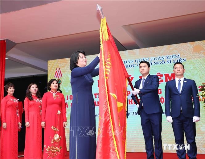 Phó Chủ tịch nước Đặng Thị Ngọc Thịnh gắn Huân chương Độc lập hạng Nhì lên lá cờ truyền thống của nhà trường. Ảnh: Thanh Tùng - TTXVN