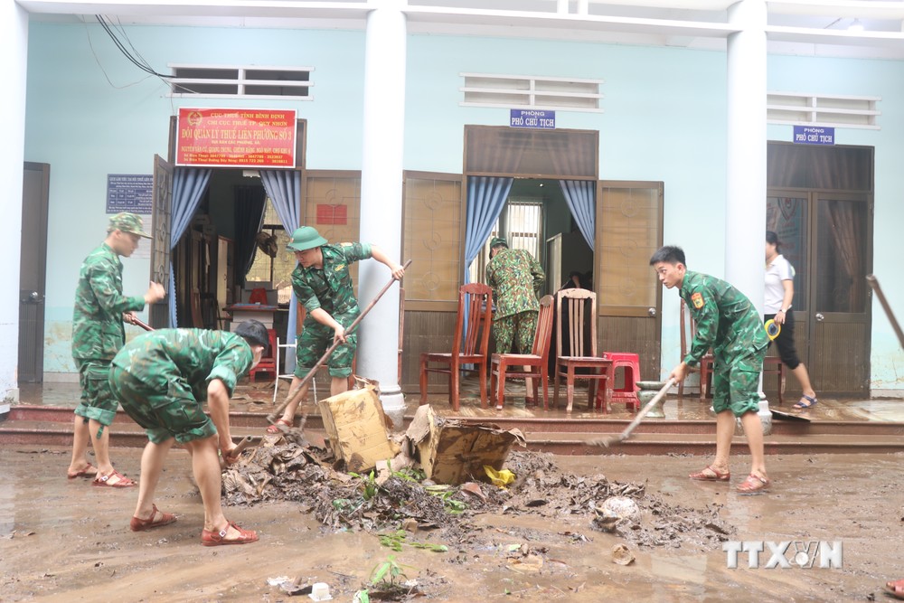 Lực lượng biên phòng cùng với cán bộ phường Ghềnh Ráng (Quy Nhơn) dọn dẹp bùn non tại trụ sở làm việc. Ảnh: Sỹ Thắng - TTXVN