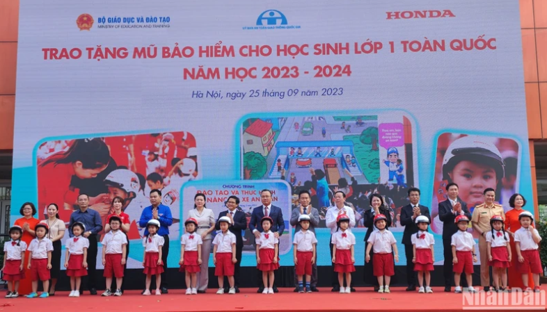 Đại diện Ban tổ chức trao tặng mũ bảo hiểm cho các em học sinh Trường tiểu học Phú Đô (Hà Nội). Ảnh: nhandan.vn