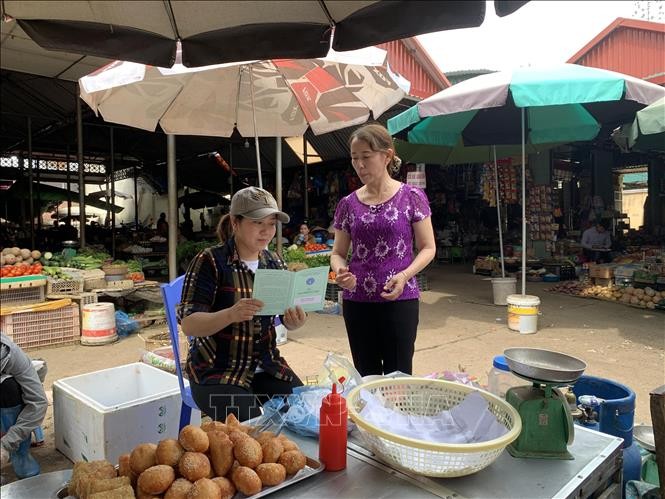Nhân viên đại lý thu bảo hiểm tuyên truyền về chính sách bảo hiểm xã hội tự nguyện cho các tiểu thương thành phố Sơn La. Ảnh: Hữu Quyết - TTXVN