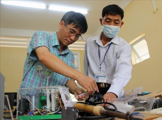 Thầy Văn Sỹ Nghi (trái) lắp ráp các bộ phận của máy trợ thở. Ảnh: Xuân Triệu - TTXVN