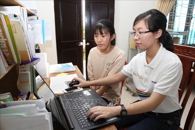 Nguyễn Thị Thu Hằng (áo trắng) tìm hiểu các kiến thức trên mạng. Ảnh: Hải Yến-TTXVN.