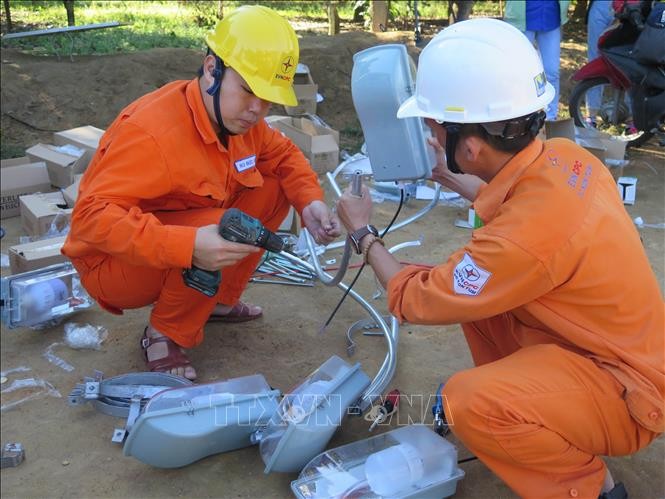 Công nhân Công ty Điện lực Kon Tum chuẩn bị vật dụng để lắp đèn chiếu sáng tại thôn Tê Rông, xã Văn Lem, huyện Đăk Tô. Ảnh: Dư Toán – TTXVN