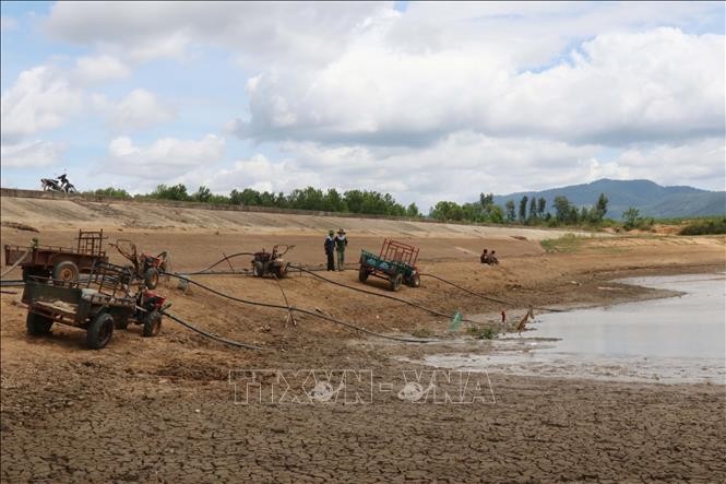Người dân thị trấn M’Đrắk, huyện M’Đrắk dùng máy bơm hút những vũng nước còn lại tại hồ Ea Kpal để chống hạn cứu lúa. Ảnh: Tuấn Anh - TTXVN