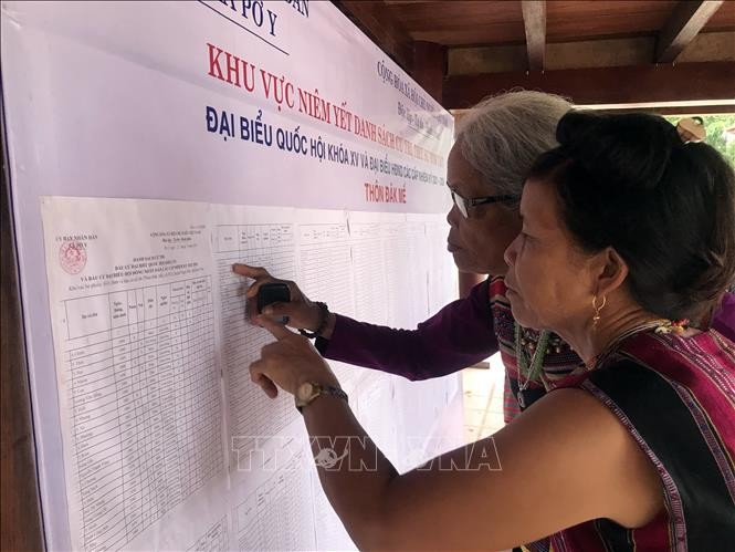 Người dân làng Đăk Mế, xã Pờ Y, huyện Ngọc Hồi (Kon Tum) xem danh sách đại biểu được niêm yết tại khu vực nhà rông. Ảnh: Khoa Chương - TTXVN