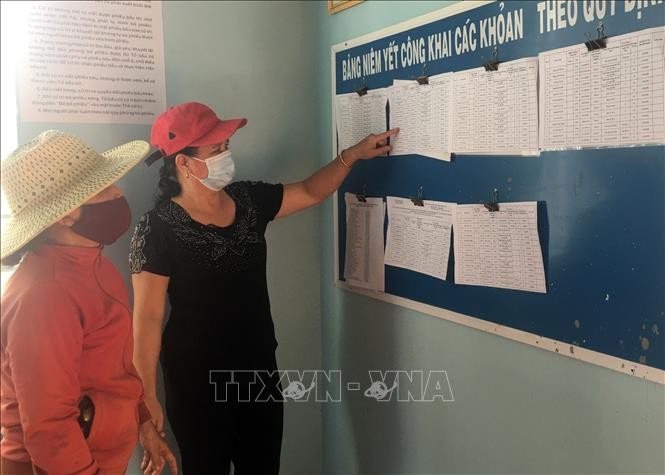 Người dân thôn 2, xã Hòa Khánh, thành phố Buôn Ma Thuột theo dõi danh sách công khai đối tượng được thụ hưởng Nghị quyết 68. Ảnh: TTXVN phát