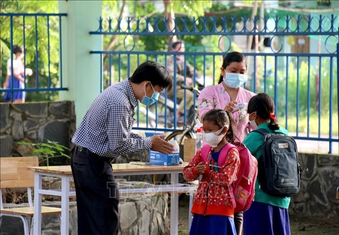 Thầy cô giáo trường Tiểu học và Trung học cơ sở Đông Tiến (xã Đông Tiến) hướng dẫn các em sát khuẩn tay trước khi vào lớp. Ảnh: Nguyễn Thanh – TTXVN