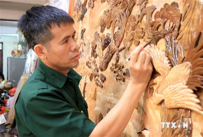Nghệ nhân ưu tú Nguyễn Văn Hùng hoàn thiện bức tranh ghép gỗ. Ảnh: Đinh Văn Nhiều - TTXVN
