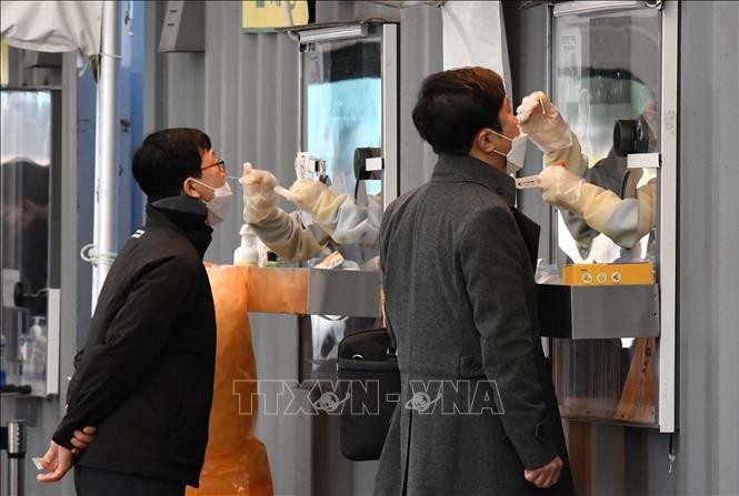 Nhân viên y tế lấy mẫu xét nghiệm COVID-19 cho người dân tại Seoul, Hàn Quốc ngày 1/12/2021. Ảnh: AFP/TTXVN
