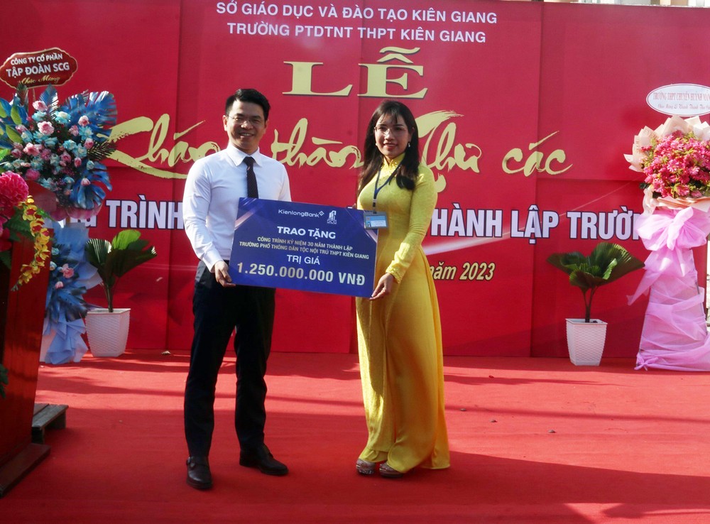 Tổng Giám đốc Ngân hàng Thương mại Kiên Long Trần Ngọc Minh trao bảng biểu trưng tặng công trình Thư các cho nhà trường Ảnh: Lê Sen – TTXVN