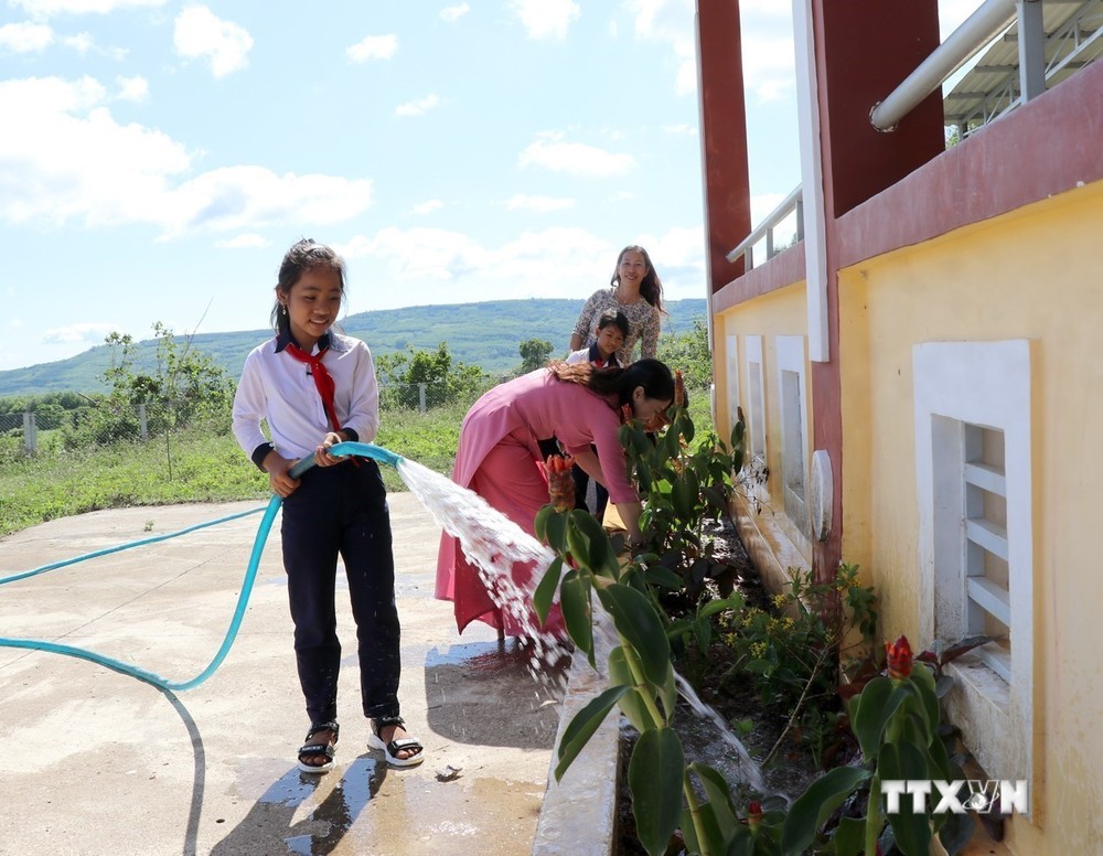 Cô và trò tại điểm trường thôn Hòa Ngãi sử dụng nước từ giếng khoan để chăm sóc hoa trong khuôn viên. Ảnh: Xuân Triệu - TTXVN